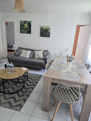 A living room with a sofa, a dining table with chairs, a coffee table, and two paintings on the wall. - Sejour eau vive, 3 bedrooms Near metro and créteil village (Créteil)