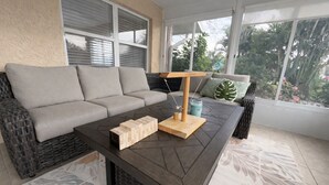 En moderne stue med sofa, sofabord og udsigt til grønne omgivelser.