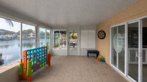 En overdækket balkon med udsigt til vand, et dartspil og børnelegetøj.