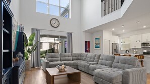 Ein geräumiges Wohnzimmer mit einem Ecksofa, einem Couchtisch und einem großen Fenster.