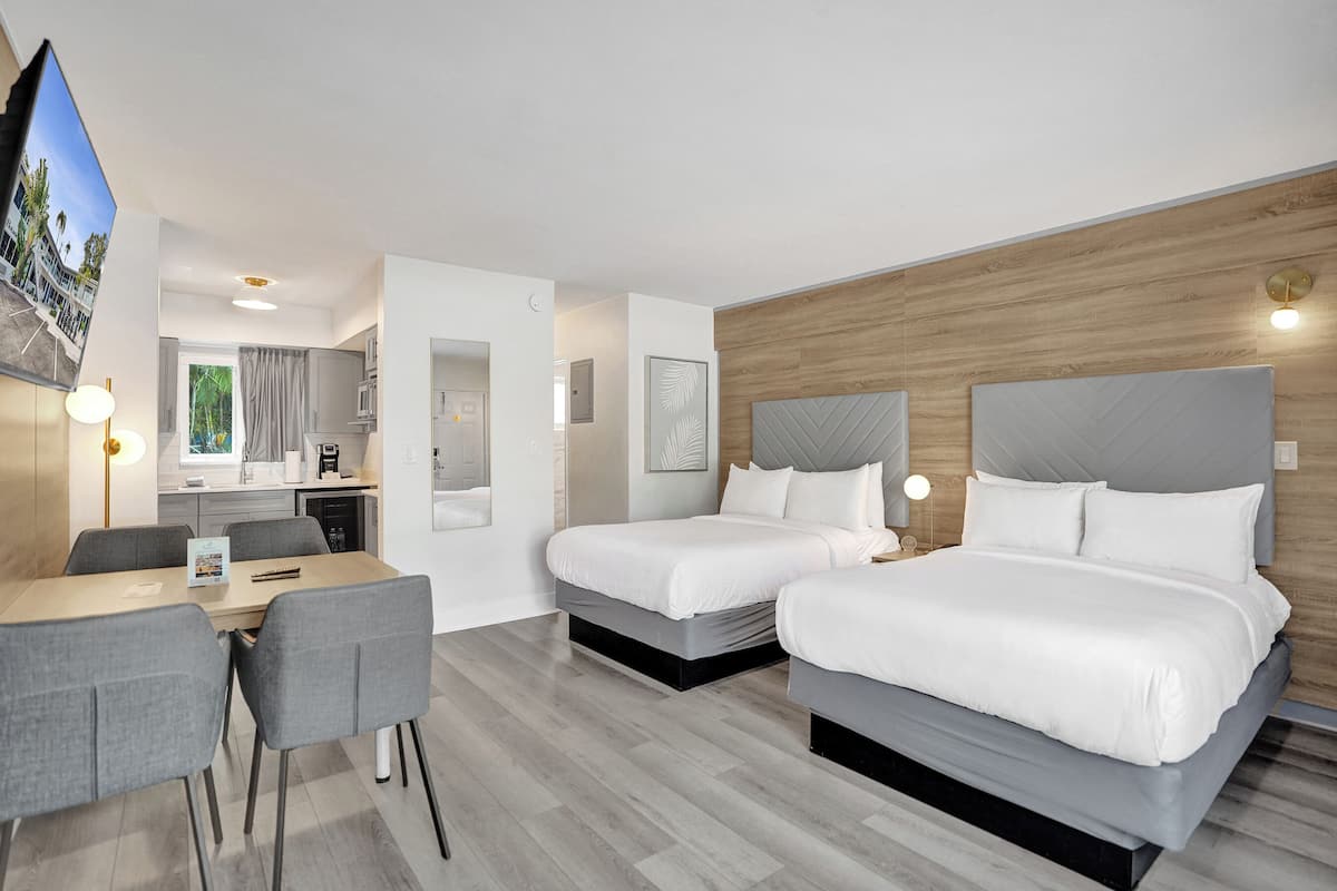 A hotel room with two beds, a dining table, and a TV.