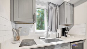 Una cocina moderna con gabinetes grises, horno integrado y una ventana con cortinas.