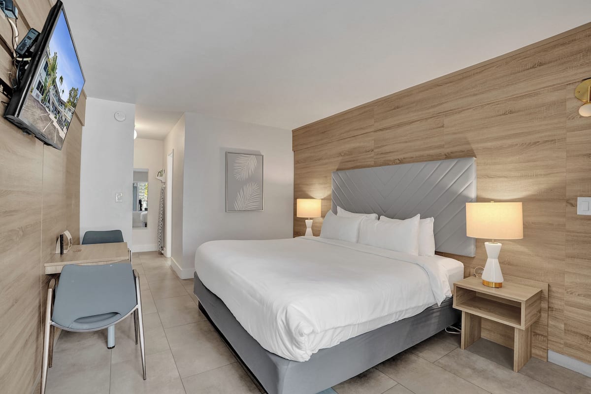 A modern hotel room with a large bed, bedside tables, a desk, and a chair.