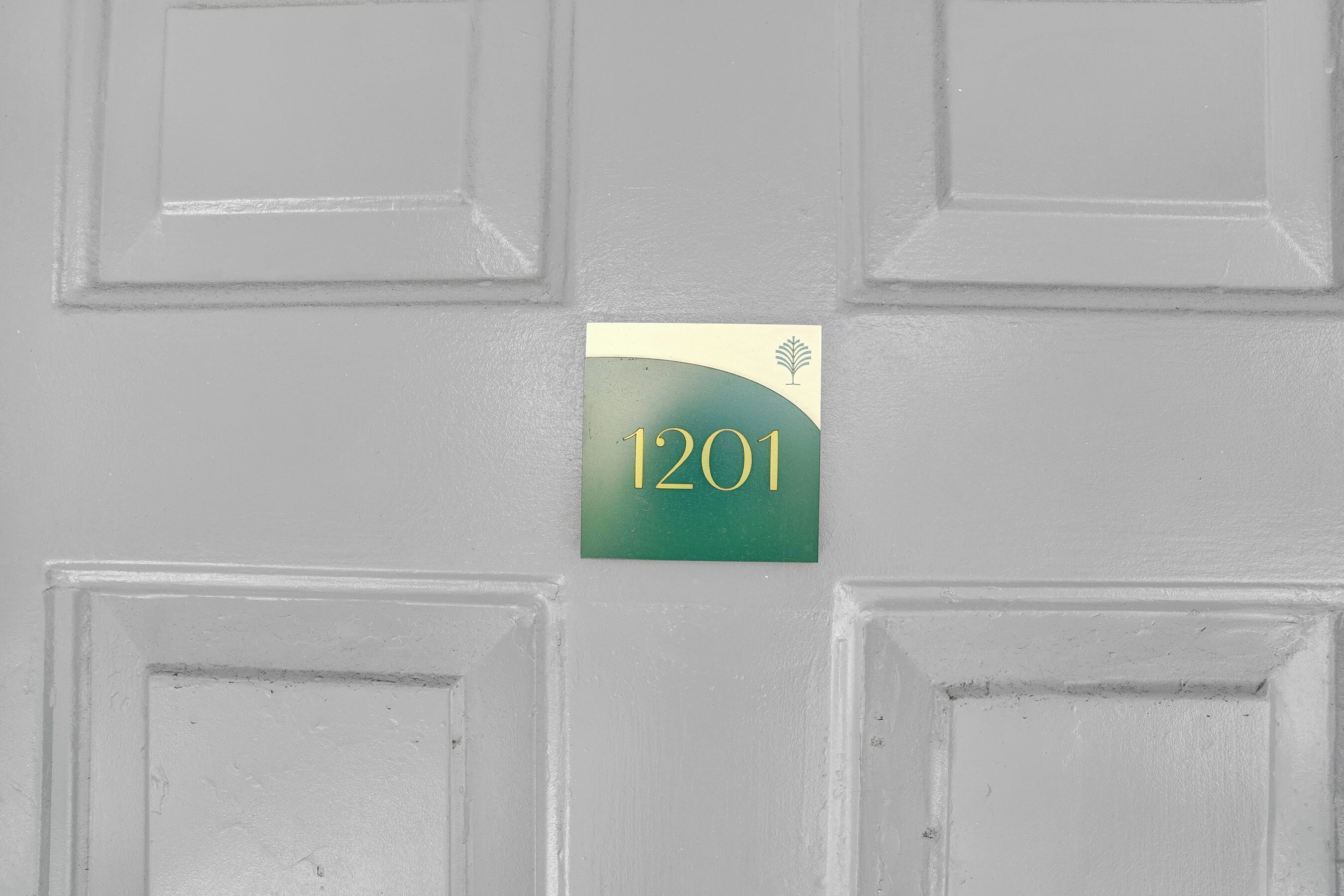 A door with a number plate displaying '1201' and a small leaf symbol.