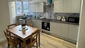 Een moderne keuken met een eettafel, stoelen en inbouwapparatuur.