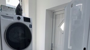 Een wasruimte met gestapelde wasmachines, een droger en een koelkast.