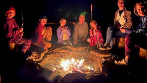 Un groupe de personnes assises autour d’un feu de camp, la nuit.
