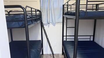A room with bunk beds, a window with curtains, and a door with a lock.