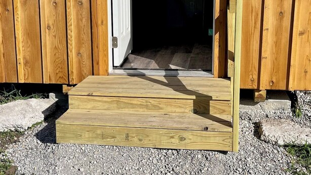 Une porte en bois avec un petit seuil menant à l’intérieur d’un bâtiment.