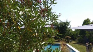 A pool with a patio area, surrounded by greenery and a house in the background. - The Presbytery Suite (PUISSEGUIN)