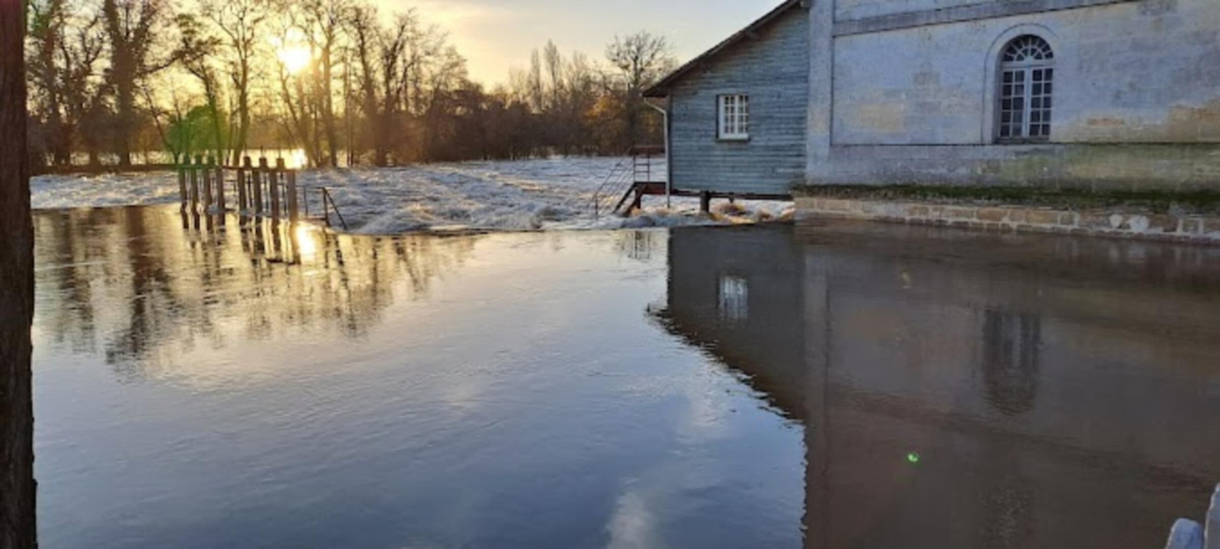 Un bâtiment doté d’une grande fenêtre et dont le reflet se mire dans l’eau.