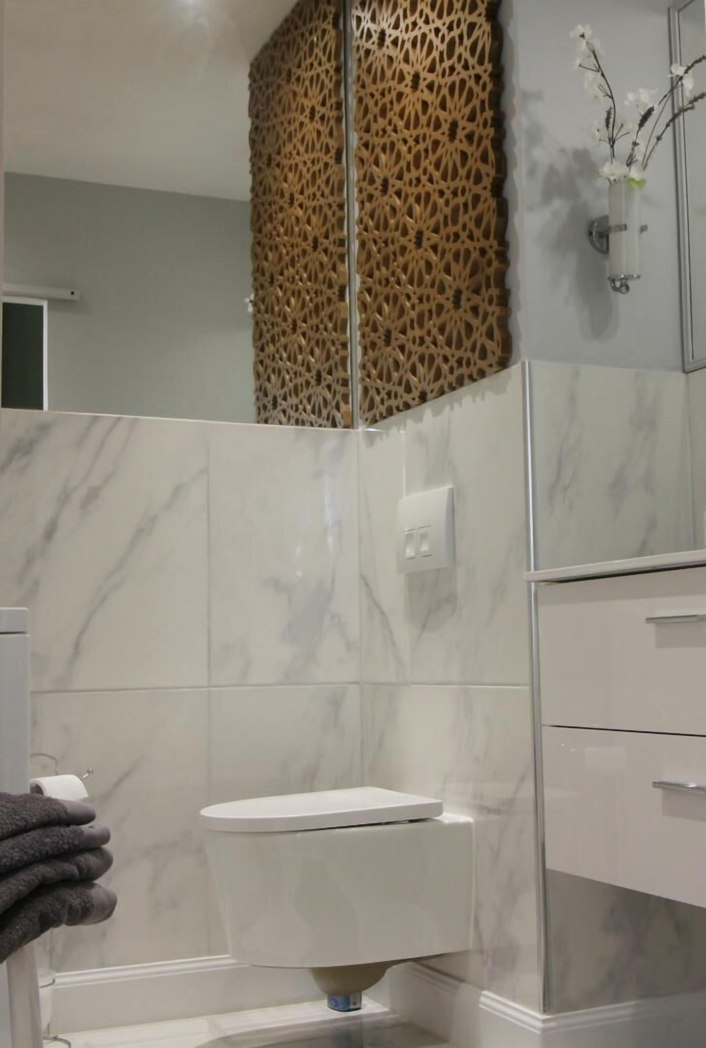 Ein modernes Badezimmer mit Toilette, Handtuchhalter und einer dekorativen Wandverkleidung.