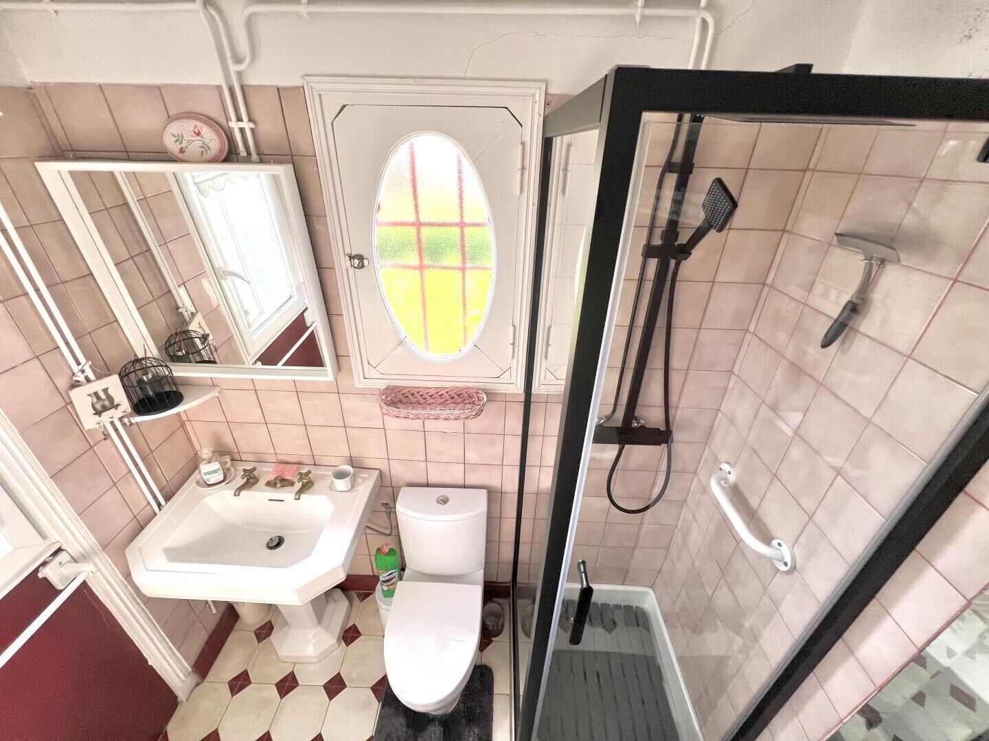 Et badeværelse med håndvask, toilet, bruser og spejl.