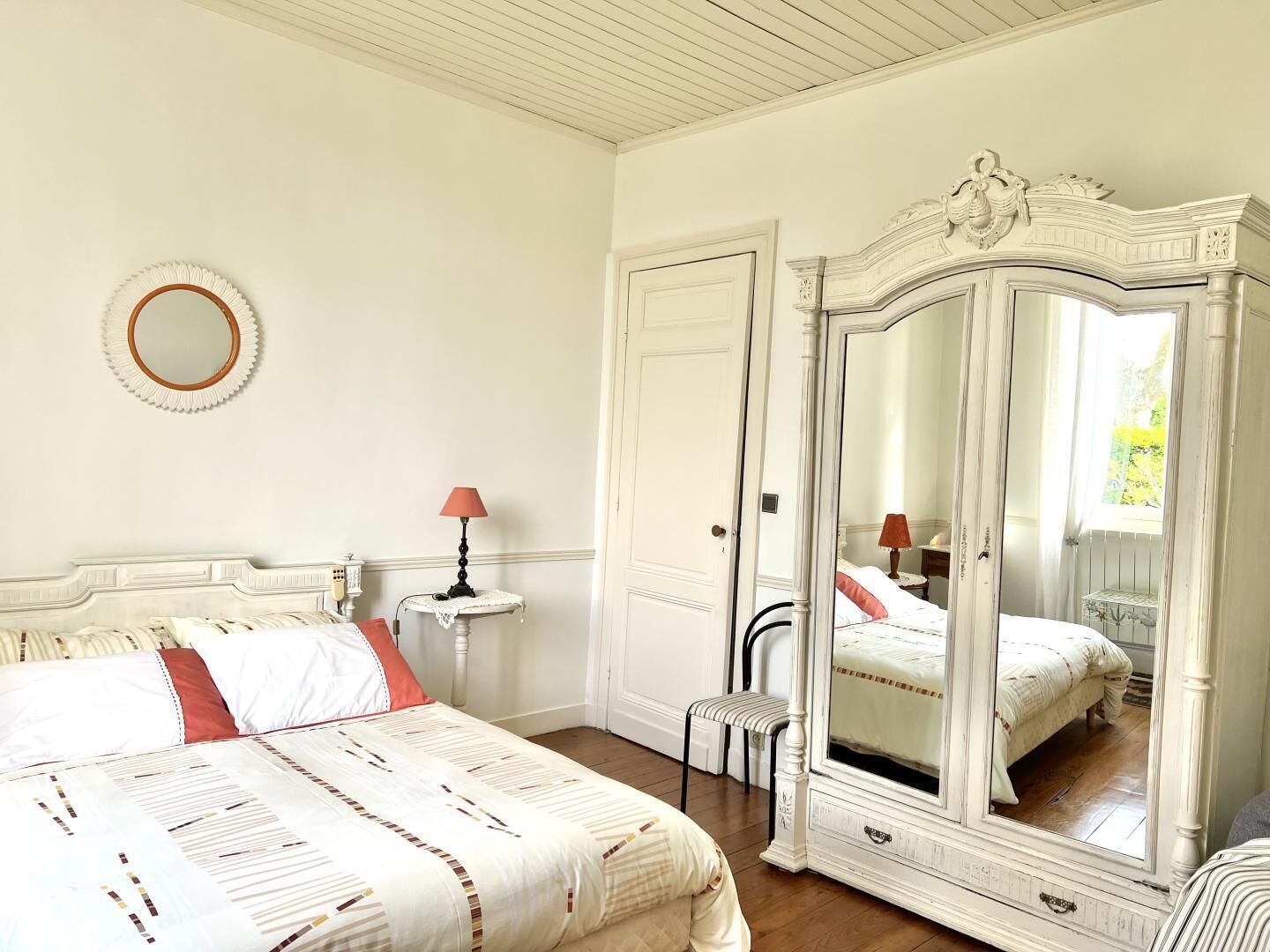 A bedroom with a bed, a dresser, a mirror, and a small table with a lamp.