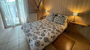 Ein Schlafzimmer mit einem Bett, zwei Nachttischlampen, einem Fenster mit Vorhängen und einer Holzbalkendecke.