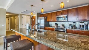 Eine moderne Küche mit Granit Arbeitsplatten, Edelstahlgeräten und Holzschränken.