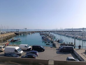 A marina with boats docked, a pier, and vehicles parked. - Sea-view studio by the port | 2 guests | Ref 2000 (ST CAST LE GUILDO)