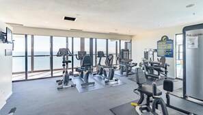 A gym with exercise equipment, large windows, and a view of the sea. - Stunning Ocean View Studio at the Golden Sands (Ocean City)