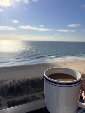 A mug with a beverage, a beach, and the ocean in the background. - Stunning Ocean View Studio at the Golden Sands (Ocean City)