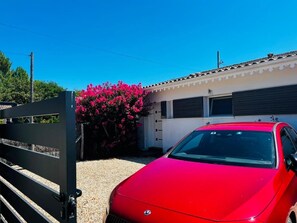 A red car parked in front of a building with a white facade and a black gate. - Sérénité d'Audenge - AUDENGE (AUDENGE)