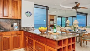 Una cocina moderna con armarios de madera, encimera de granito y vista al océano.