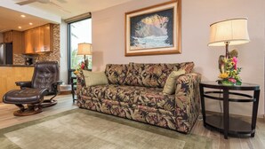 Una sala de estar con un sofá, un sillón reclinable, una lámpara y un cuadro en la pared.