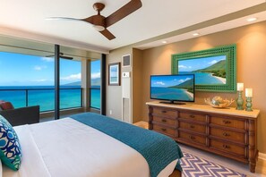Ein Schlafzimmer mit einem großen Bett, einem Fernseher, einer Kommode und Meerblick.
