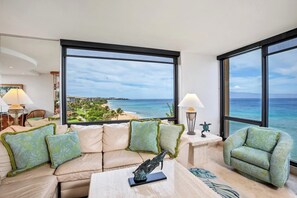 Ein modernes Wohnzimmer mit großem Fenster und Blick auf Strand und Meer.