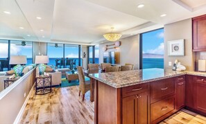 A modern kitchen with a large island, wooden cabinets, and a view of the ocean. - Mahana Villas | Oceanfront 4 BR Sleeps 10 | Car Incl. w/ 6+ Nights | MAH ML-3758 by KBM (Lahaina)