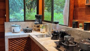 Une cuisine dotée d’une grande fenêtre, d’une machine à café, d’une cuisinière et d’un évier.
