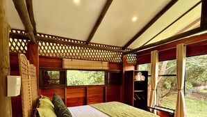 Une pièce de cabane en bois comprenant un lit, un banc, une fenêtre avec des rideaux et un ventilateur de plafond.