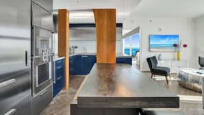 A modern kitchen with stainless steel appliances, a central island, and blue cabinetry. - Bay View 2BR at The Arya Coconut Grove (Miami)