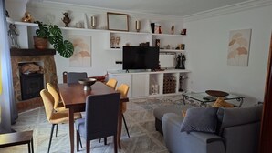 Un salon avec une cheminée, une table à manger avec des chaises, un canapé et un téléviseur posé sur un meuble.