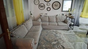 Un salon avec des canapés à rayures, un tapis à motifs et plusieurs horloges murales.