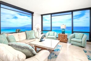 Ein Wohnzimmer mit einem großen Fenster, einem Sofa, einem Couchtisch und einem Sessel.