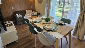 A dining area with a table set for four, a sofa, and a television in the corner.