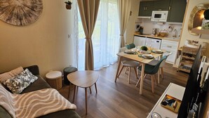 A compact living space with a sofa, a small dining table, a TV, and a kitchen area.