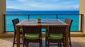 Ein Balkon mit Tisch und Stühlen, Blick auf ein klares, blaues Meer und die Ferne.
