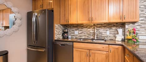 A modern kitchen with wooden cabinets, stainless steel appliances, and a tiled backsplash.