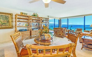 A dining area with a round table, chairs, and a view of the ocean. - Mahana Villas | Oceanfront 5 BR Sleeps 15 | Car Incl. w/ 6+ Nights | MAH ML-3888 by KBM (Lahaina)
