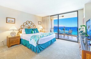 A hotel room with a bed, a TV, a balcony with a view of the ocean, and a dining area. - Mahana Villas | Oceanfront 5 BR Sleeps 15 | Car Incl. w/ 6+ Nights | MAH ML-3888 by KBM (Lahaina)