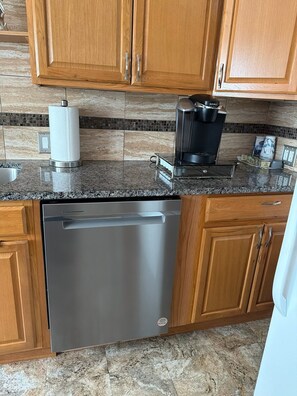 A kitchen with wooden cabinets, a stainless steel dishwasher, a coffee maker, and a paper towel holder. - Quiet cozy 2-bedroom apartment with AC in vibrant Skokie (Skokie)