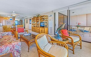 A spacious living area with wicker furniture, a television, and a dining area with chairs. - Mahana Villas | Oceanfront 7 BR Sleeps 21 | Car Incl. w/ 6+ Nights | MAH ML-3890 by KBM (Lahaina)