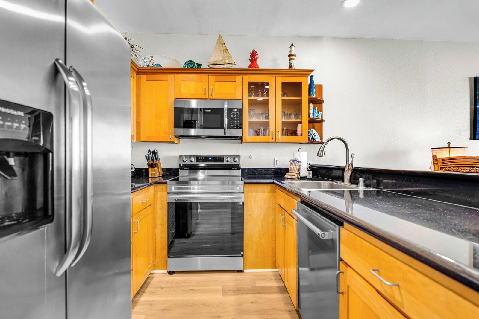 Een moderne keuken met roestvrijstalen apparatuur, houten kastjes en een zwart aanrecht.
