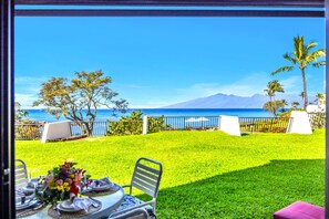 A dining area with a view of the ocean and mountains. - Napili Point | Oceanfront 3 BR, Sleeps 12 | Car Incl. w/ 6+ Nights | NAP ML-3924 by KBM (Lahaina)