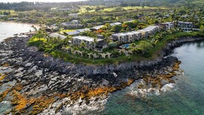 Ett hotell vid kusten med flera byggnader, en klippig strand och klart vatten.
