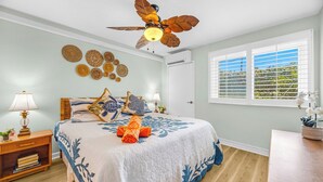 A bedroom with a bed, a ceiling fan, a window with blinds, and wall decor. - Napili Point | Oceanfront 4 BR, Sleeps 16 | Car Incl. w/ 6+ Nights | NAP ML-3930 by KBM (Lahaina)