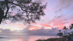 A coastal view with a sunset, palm trees, and a body of water. - Napili Point | Oceanfront 4 BR, Sleeps 16 | Car Incl. w/ 6+ Nights | NAP ML-3930 by KBM (Lahaina)