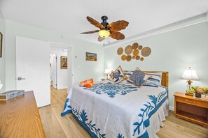 A bedroom with a bed, a ceiling fan, a wall with decorative plates, and a nightstand with a lamp. - Napili Point | Oceanfront 3 BR, Sleeps 12 | Car Incl. w/ 6+ Nights | NAP ML-3933 by KBM (Lahaina)
