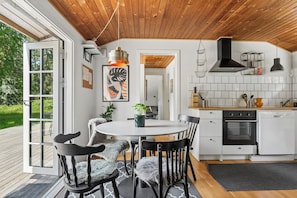 A modern kitchen with white cabinets, a black stove, and a wooden ceiling.